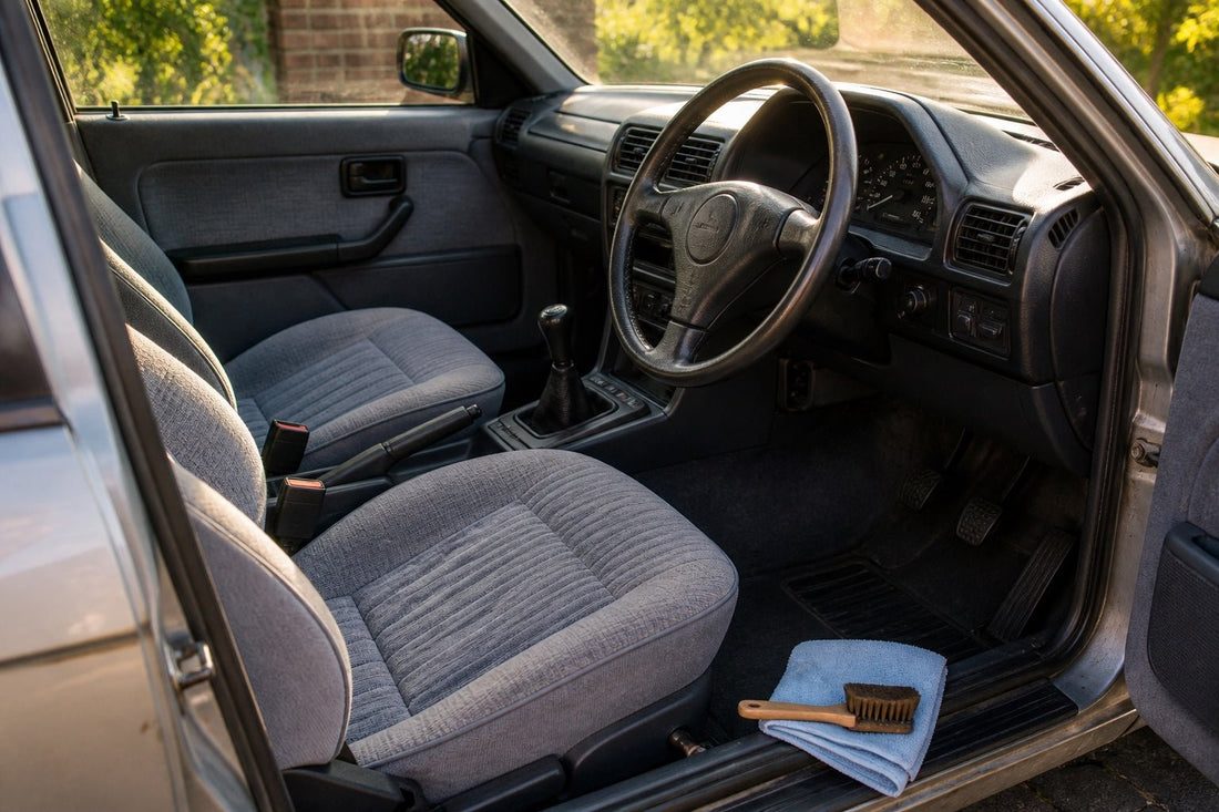 Well-kept older right-hand-drive car interior with clean fabric seats, detailing brush and folded cloth