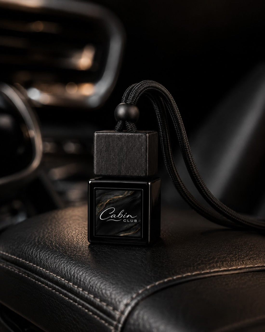 Cabin Club car fragrance diffuser resting on the black leather centre armrest of a refined car interior
