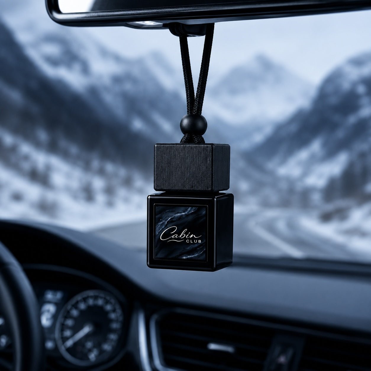 Cabin Club Ice Drive car fragrance diffuser hanging from a rear-view mirror on a snowy mountain road