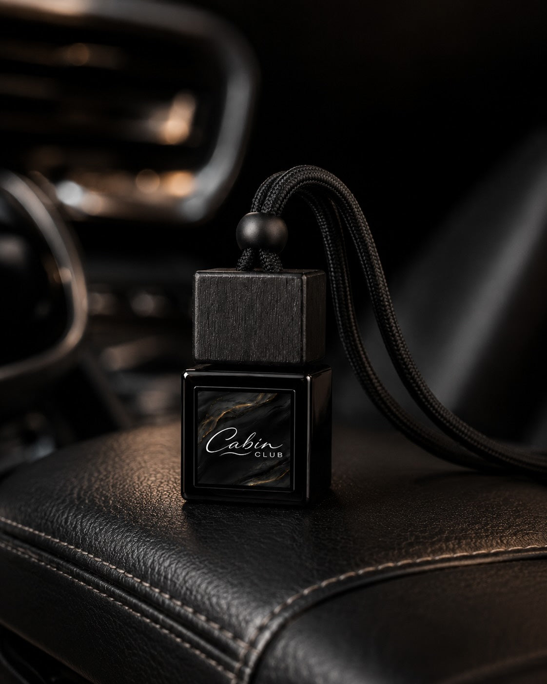 Cabin Club car fragrance diffuser resting on a black leather centre armrest